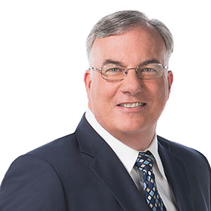 John is a white male wearing a suit and glasses.